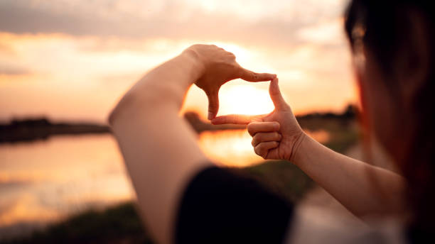 istock Future planning concept, Close up of woman hands making frame gesture with sunset. 1363722800