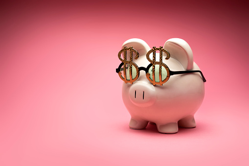This is a photo of a large white piggy bank on a pink background. This is a concept photo related to finance.