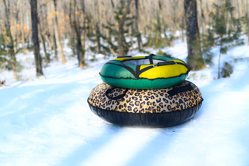 Two donuts for tubing on snow in forest without people. Winter activity