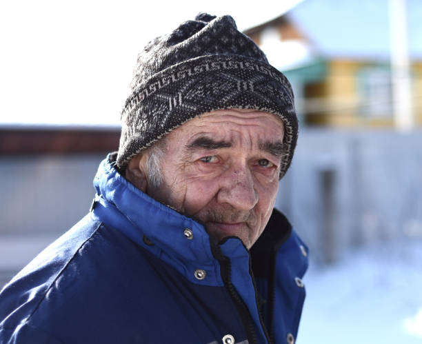 Portrait of old Russian man looking sadly in the camera on winter background stock photo