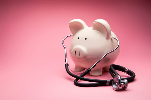 This is a photo of a large white piggy bank on a pink background. This is a concept photo related to finance and the medical hospital industry,