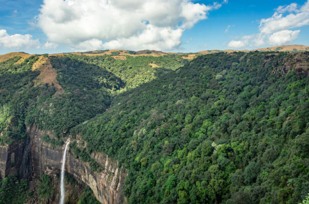 istock waterfall streams falling from mountain top covered with green forests and blue sky at day 1363725946