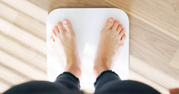 close up of woman weighing on scale to measure her weight