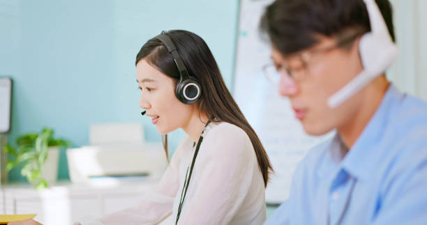 service phone operator female service phone operator in headset sit at shared desk use laptop answers incoming calls talk with client provide professional support to customers telephone worker stock pictures, royalty-free photos & images