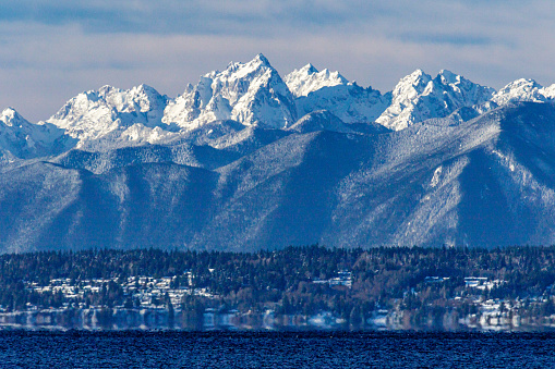 The Olympic Mountains tower over homes on the peninsula after an unprecedented snow storm.