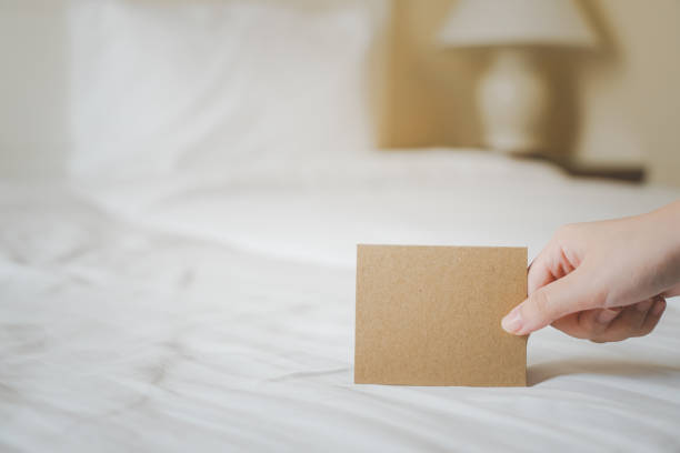 istock hand holding blank brown grunge paper for adding text  put on bed in blurred bedroom background 1363731317