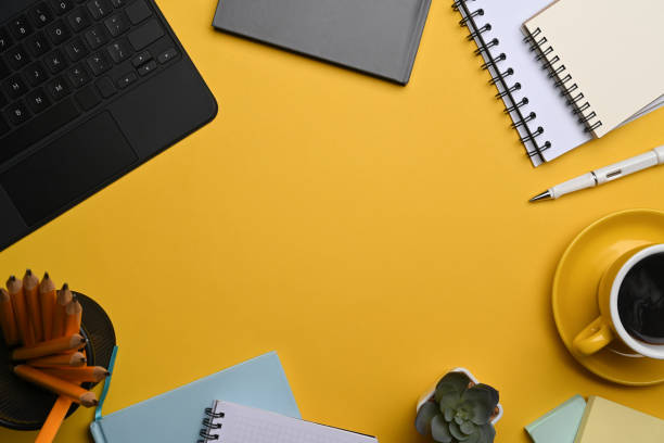 istock Above view computer laptop, coffee cup and stationery on yellow background. 1363733127