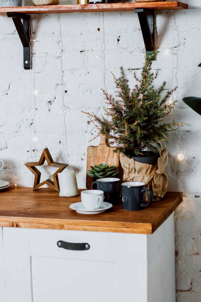 istock A small Christmas tree in a pot on a kitchen set. Mugs and a cup and saucer on the table top. 1363733202