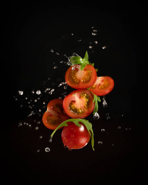 istock Levitating cherry tomatoes with arugula leaves and water splash on black background 1363734032
