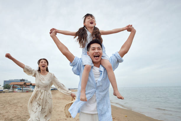 drei spielen am strand - couple two parent family beach loving stock-fotos und bilder