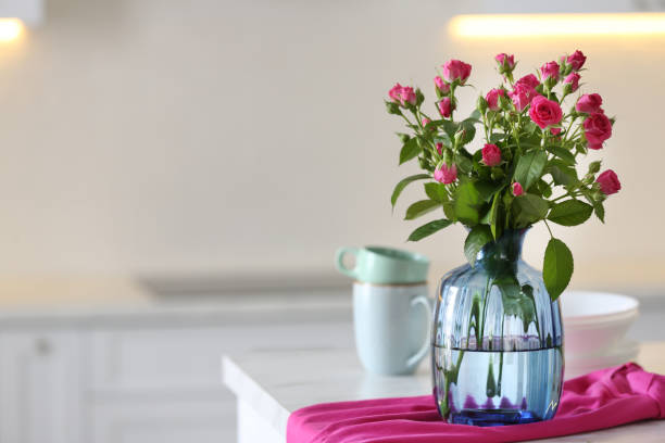 istock Glass vase with fresh flowers and towel on table in kitchen. Space for text 1363736014