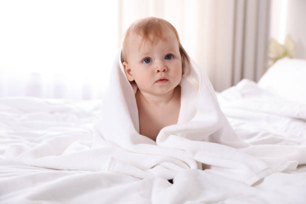 istock Cute little baby with soft towel on bed after bath 1363736749