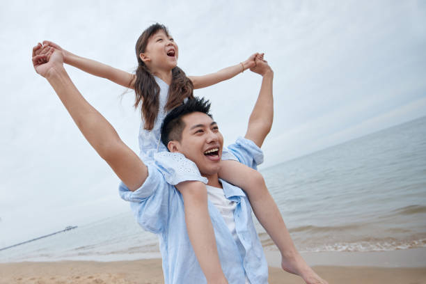 Pai e filha felizes brincando na praia - foto de acervo