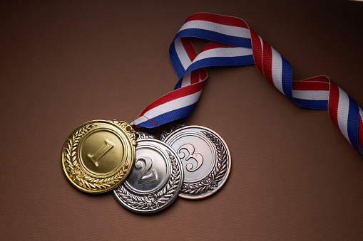 Gold medal with ribbon on many question marks background.