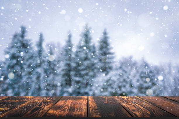 istock Winter forest with wooden table background. Blurred snow landscape and empty rustic table for product or merchandise. 1363742966
