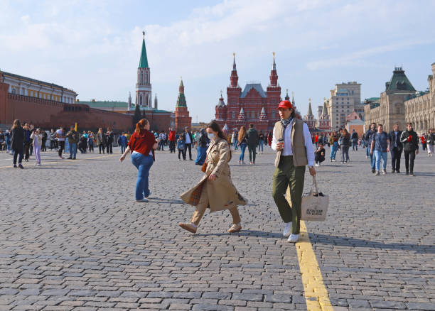 Moscow, Russia: Walking tourists on Red Square. Crowd of tourists. Young woman wearing face mask. Moscow, Russia - April 17, 2021: Walking tourists on Red Square. moscow stock pictures, royalty-free photos & images