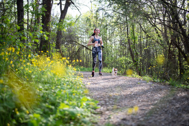 istock Young woman jogging in spring forest with her dog. 1363744871
