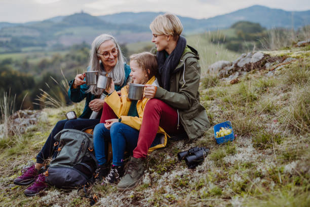 petite fille avec mère et grand-mère assises et buvant du thé chaud au sommet de la montagne. - base relief photos et images de collection