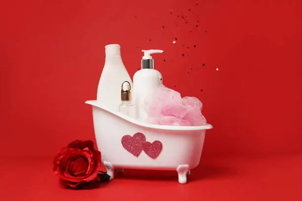 Photo of Valentine bath with cosmetic skin care products. Shampoo, lotion, essential oil in beautiful bath with rose and hearts.Romantic gift for Valentine's Day