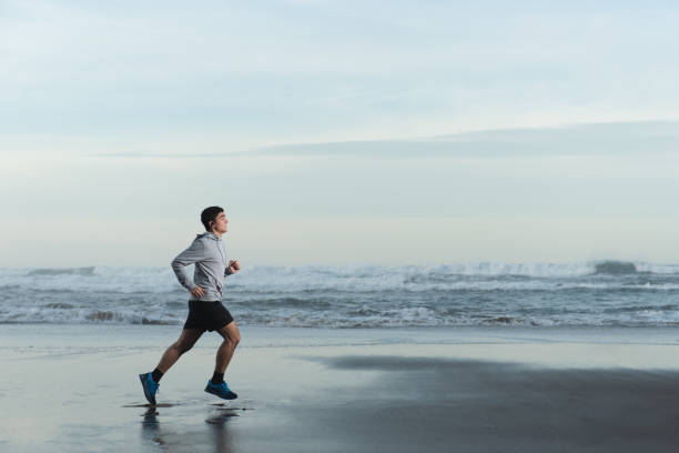 istock Hispanic young man running at the beach 1363747386