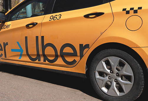 Moscow, Russia - May 01, 2021: Yellow taxi with Uber logo on the street. Uber car with inscription on it.