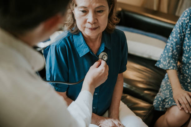 primo piano, il medico asiatico si concentra sull'ascolto del battito cardiaco della donna anziana. - respiratory system foto e immagini stock