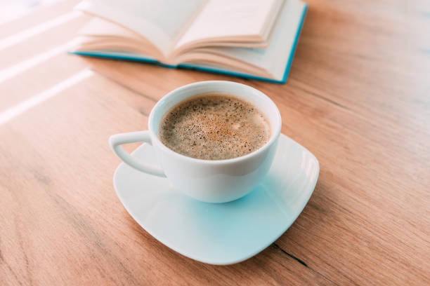 istock Coffee cup on the table, open book in background 1363750326