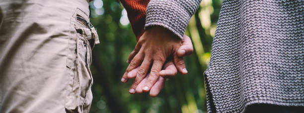 Banner header Close up of man and woman couple hands holding each other together with love and relationship and green woods nature forest in background - concept of friendship and healthy lifestyle stock photo