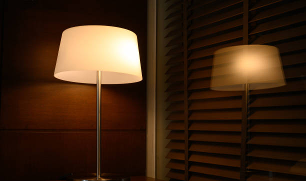 istock lamp or lantern glowing on wooden table next to bed with reflection glass. 1363754380