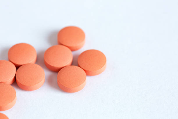 istock Orange round pills close-up, medicines on a white background, top view, copy space 1363754384
