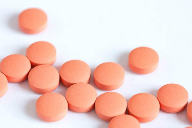 istock Orange round pills close-up, medicines on a white background, top view, copy space 1363754411