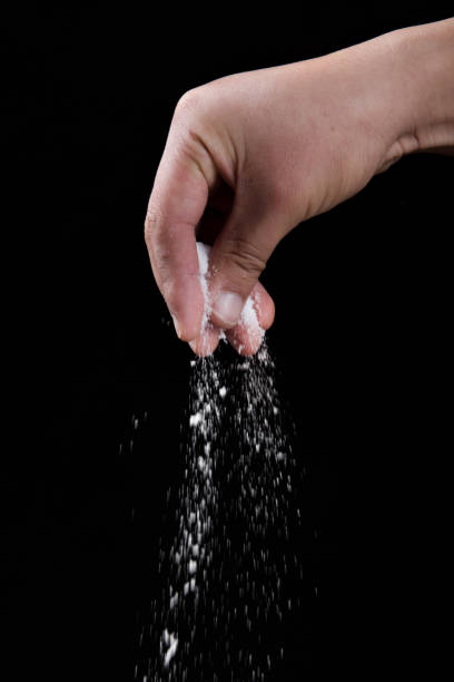 istock Male hand sprinkles salt on black background. 1363754420