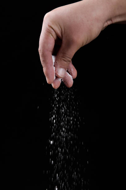 istock Male hand sprinkles salt on black background. 1363754421