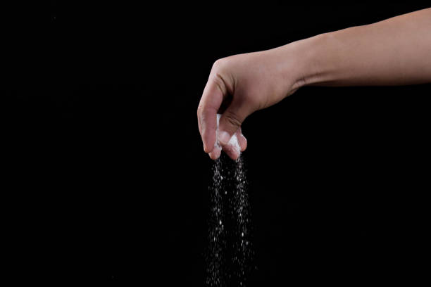 istock Male hand sprinkles salt on black background. 1363754424