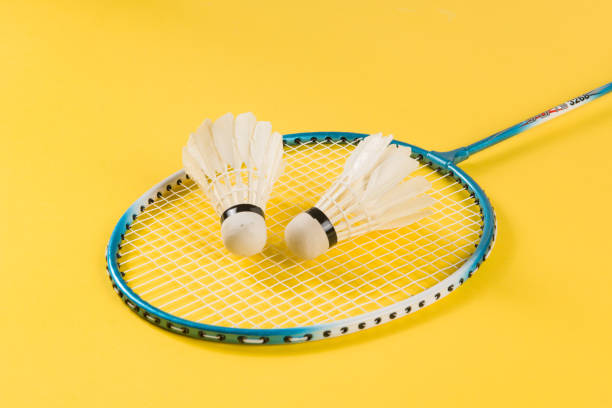 Badminton shuttlecock and badminton racket on yellow background Badminton shuttlecock and badminton racket on yellow background badminton racket stock pictures, royalty-free photos & images