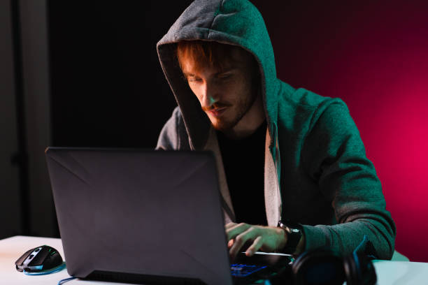 istock Professional hacker with laptop sitting at table on dark background 1363756530