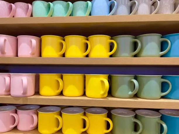 Colourful ceramic mugs displayed for sale in a shop. Handicraft concept.