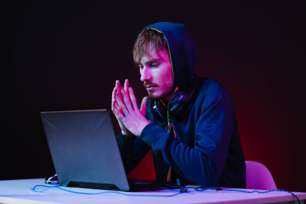 istock Professional hacker with laptop sitting at table on dark background 1363756673