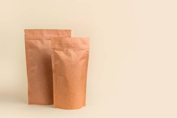 istock Pouch bags mockup neutral beige background monochrome. Merchandise packaging. Blank brown kraft paper pack demonstration 1363757155