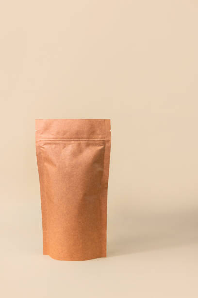 istock Pouch bag mockup neutral beige background monochrome. Merchandise packaging. Blank brown kraft paper pack demonstration. 1363757157