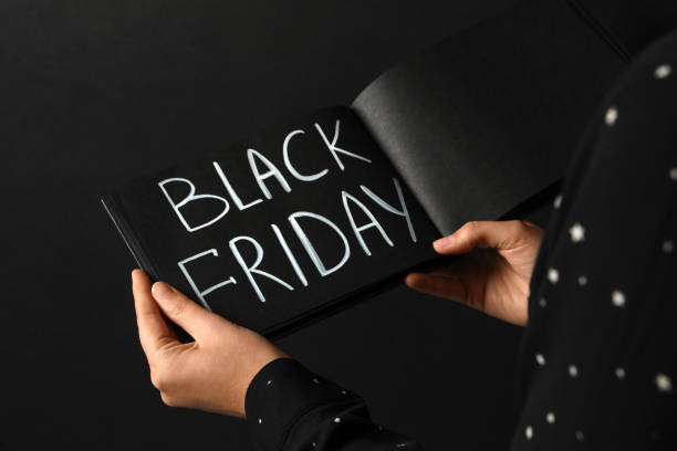 istock Woman holding notebook with words Black Friday on dark background, closeup 1363761543