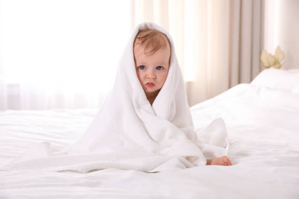 istock Cute little baby with soft towel on bed after bath 1363761912