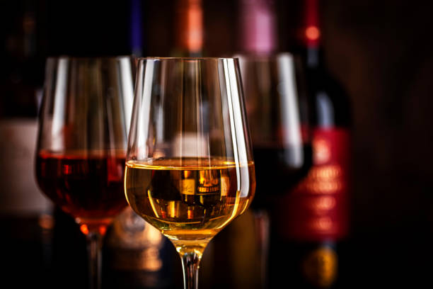 red, white and rose wine in glasses on wooden background and collection of wine bottles, copy space - garrafa de vinho imagens e fotografias de stock