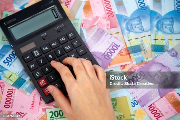 Hand Typing On Calculator In Paper Currencies Background Stock Photo - Download Image Now