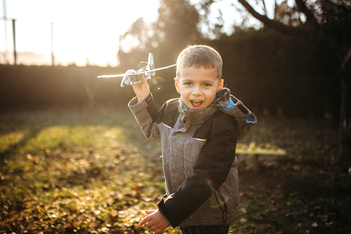 Cute little boy playing with airplane toy outdoors