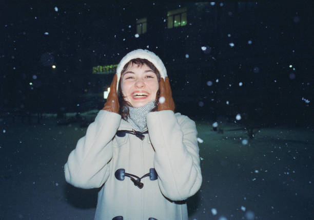 Young Caucasian woman standing  under the snow in the evening