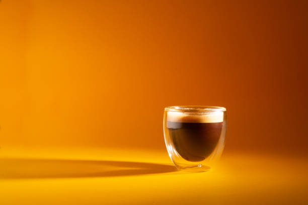 Freshly brewed creamy espresso in a glass coffee cup isolated on yellow background, close up with copy space Freshly brewed creamy espresso in a glass coffee cup isolated on yellow background, close up with copy space black coffee stock pictures, royalty-free photos & images