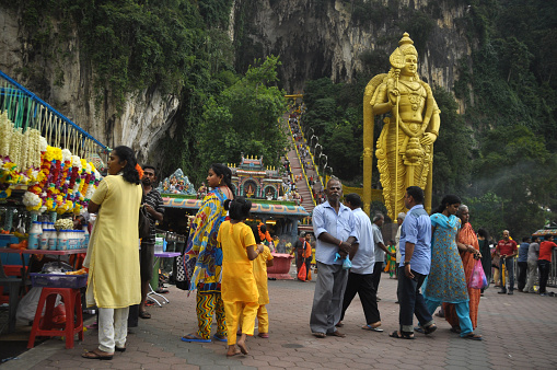 Kuala Lumpur, Malaysia - February 2, 2015: Worshippers and tourists in front of the statue of Murugan, son of Hindu god Shiva, at Batu Caves in Kuala Lumpur, Malaysia.