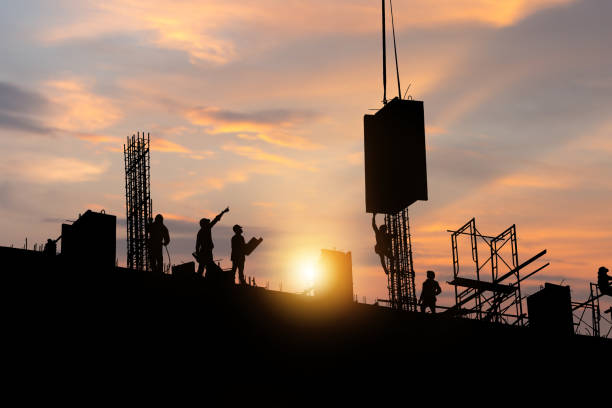 istock Silhouette of Engineer and worker checking project at building site background, construction site at sunset in evening time 1363767097