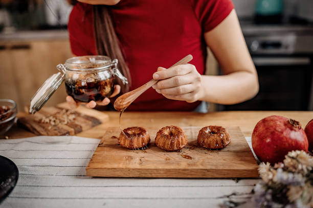 Young unrecognisable woman decorating her cakes with a honey